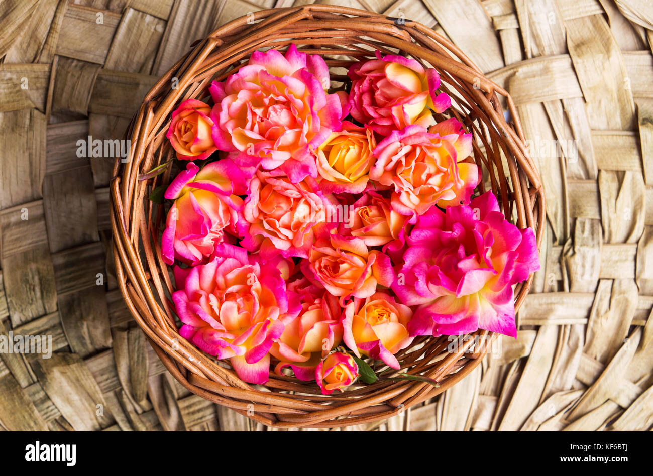 Red and orange roses in a wicker bowl Stock Photo