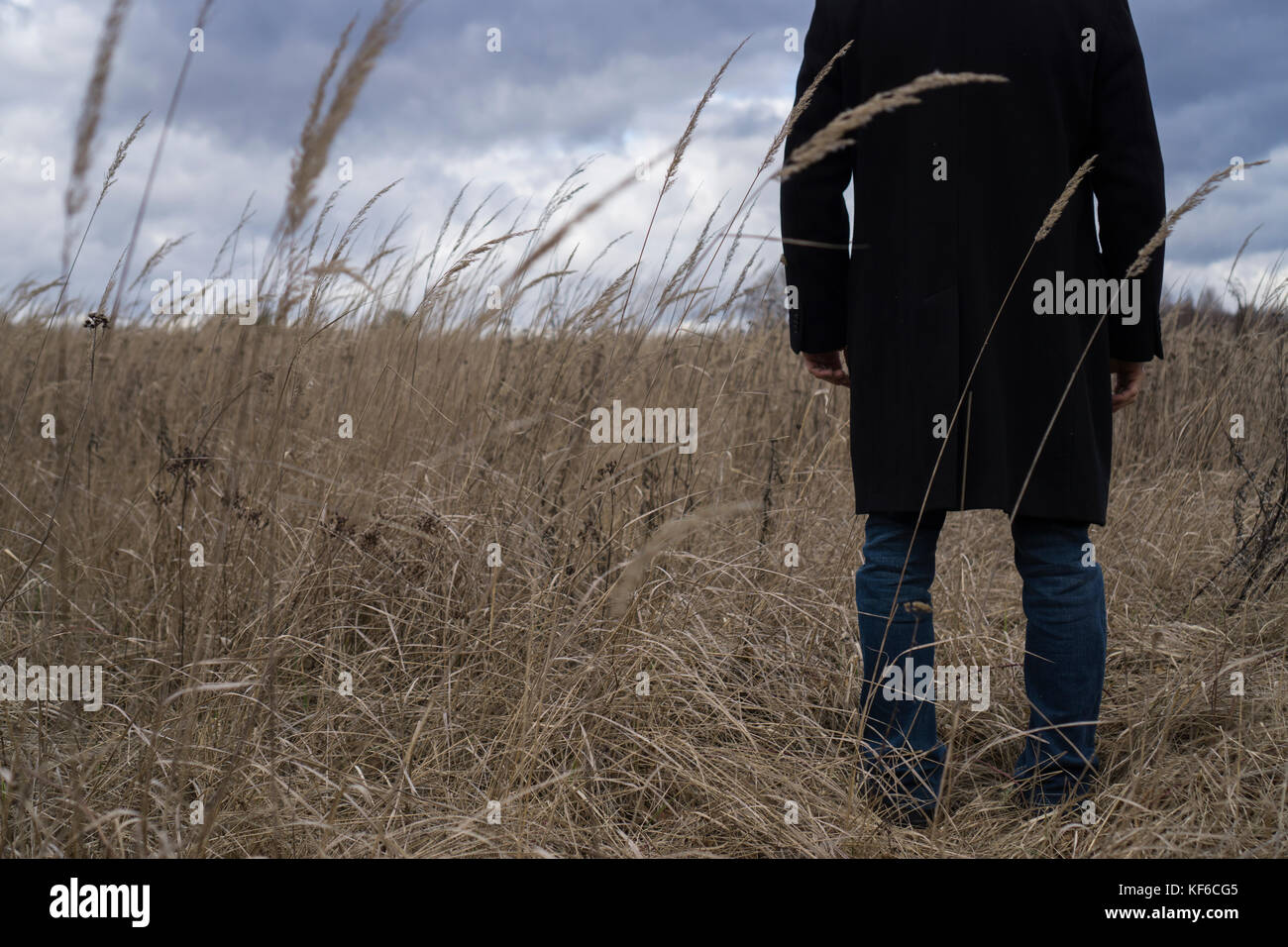 Back close up of a man wearing a coat standing in a field Stock Photo