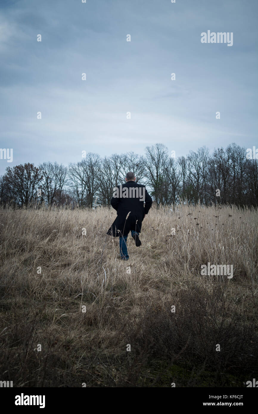Rear view of a man running away in a field Stock Photo - Alamy