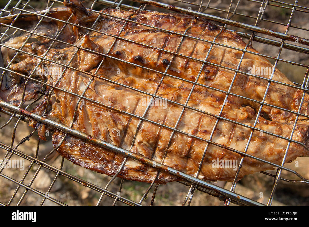 Fresh fish with sauce cooked on an open flame grill. Roasted fish with