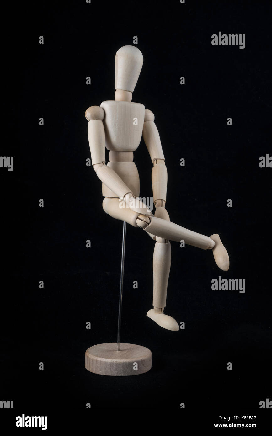 wooden mannequin sitting on black background in horizontal profile Stock  Photo