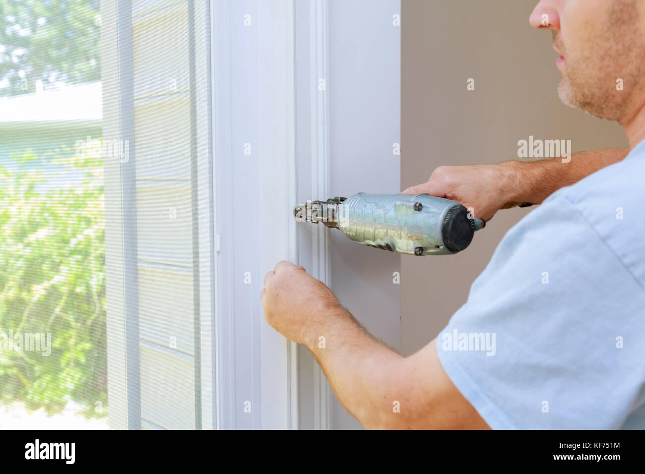 Carpenter using a brad nail gun to complete framing trim Air gun for