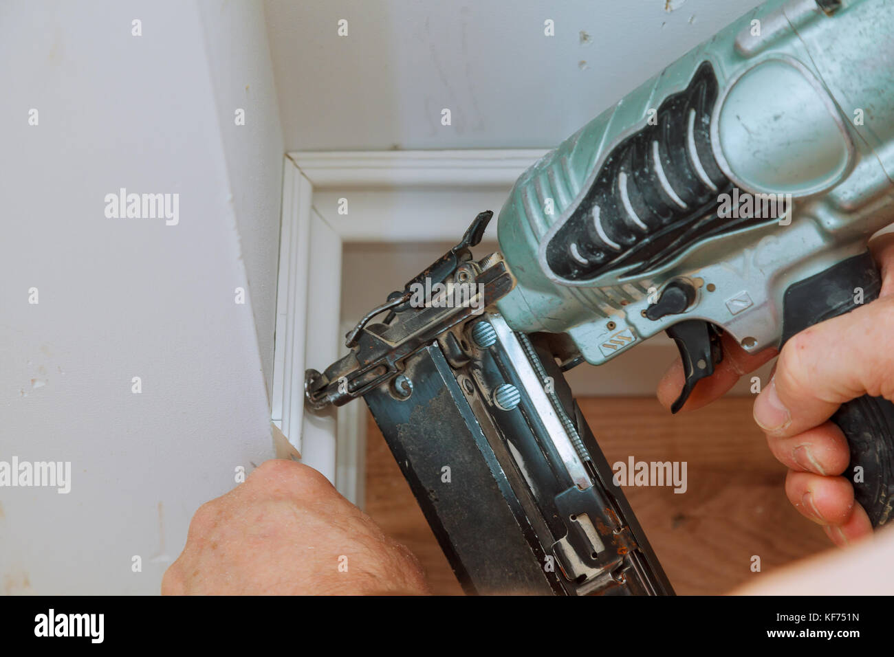 Carpenter brad using nail gun to Moulding framing trim, with the