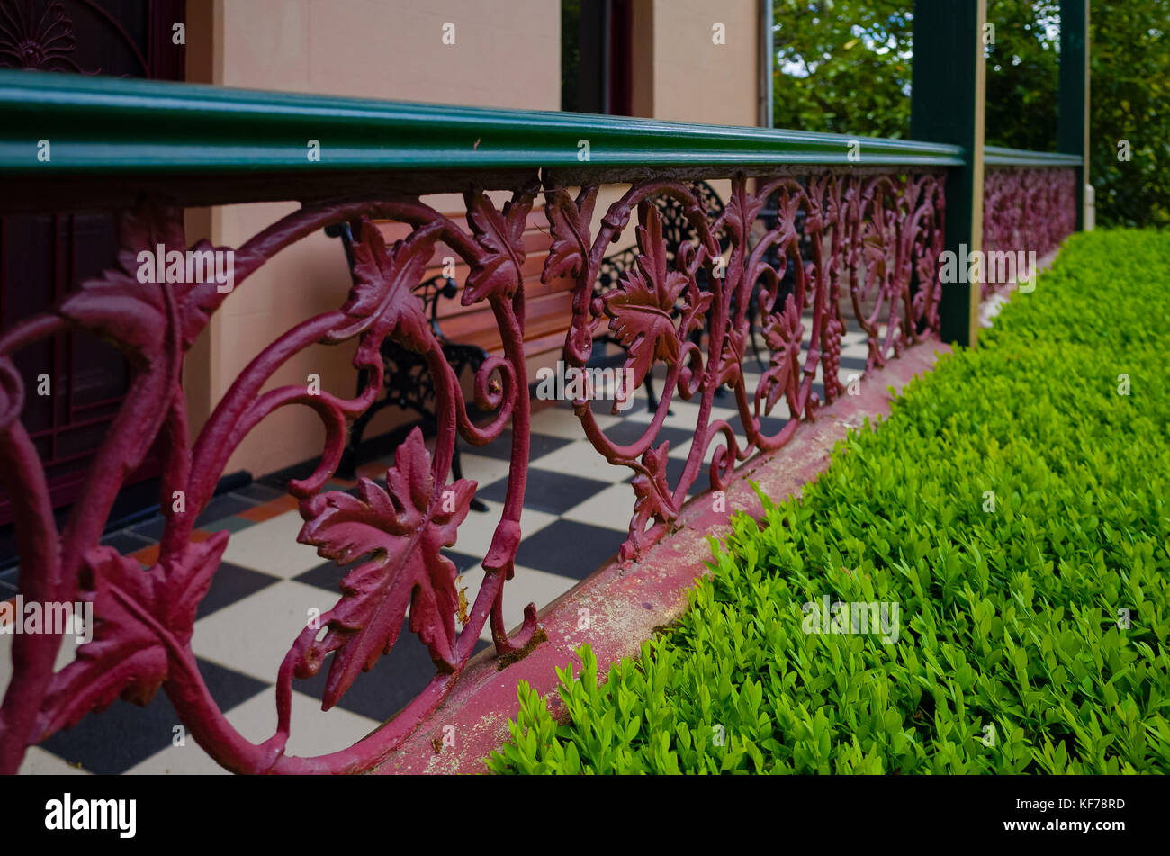 Old vintage metal railing with leaf patterns and a green hedge in front ...