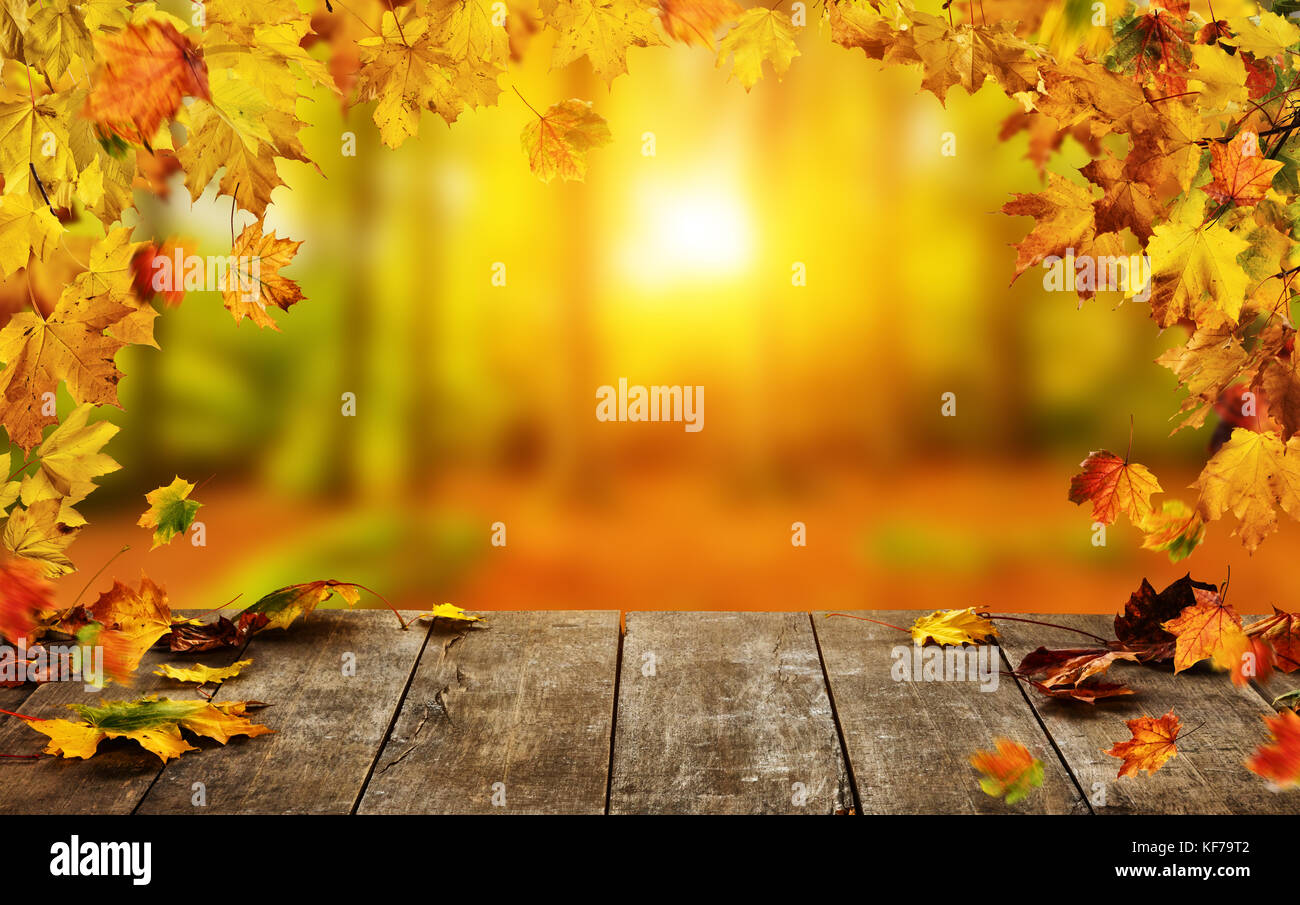 Autumn background with falling leaves and empty wooden table,  ideal for product placement or free space for text. Seasonal abstract vivid colored bac Stock Photo