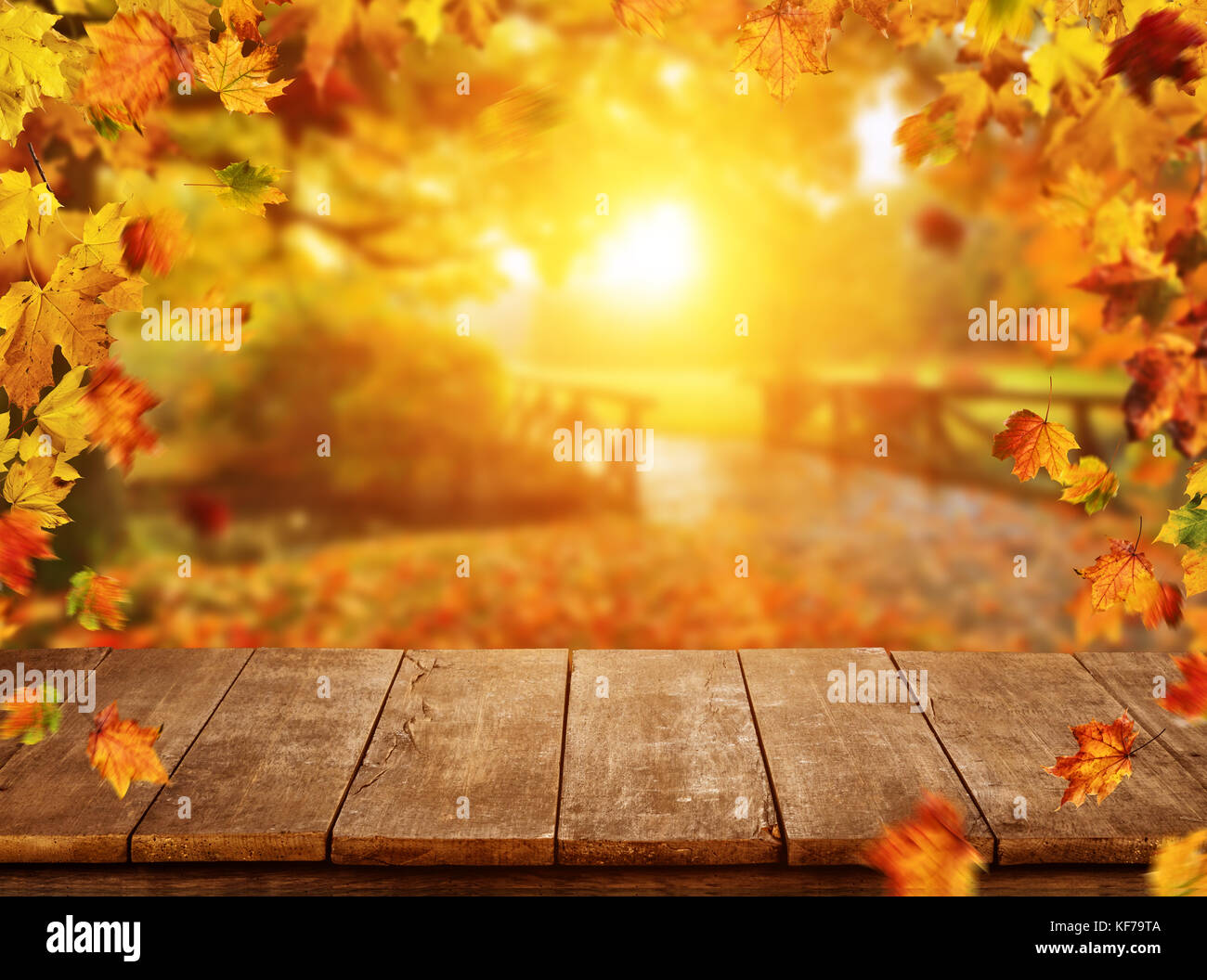 Autumn background with falling leaves and empty wooden table,  ideal for product placement or free space for text. Seasonal abstract vivid colored bac Stock Photo