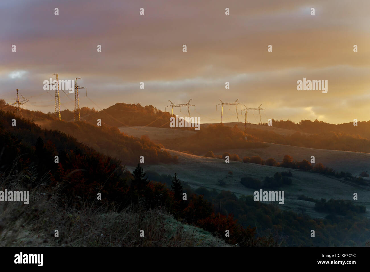 Tower of power lines in the pre-dawn mist on the outskirts mountain mist haze power line Stock Photo