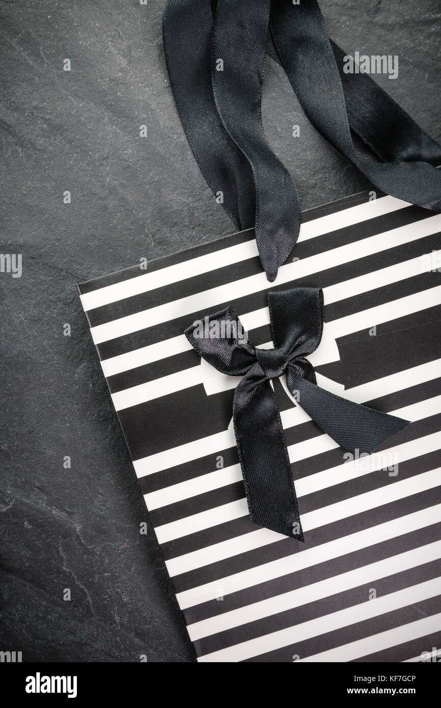 White packet in black stripes with handles ribbons and a black bow vertical Stock Photo