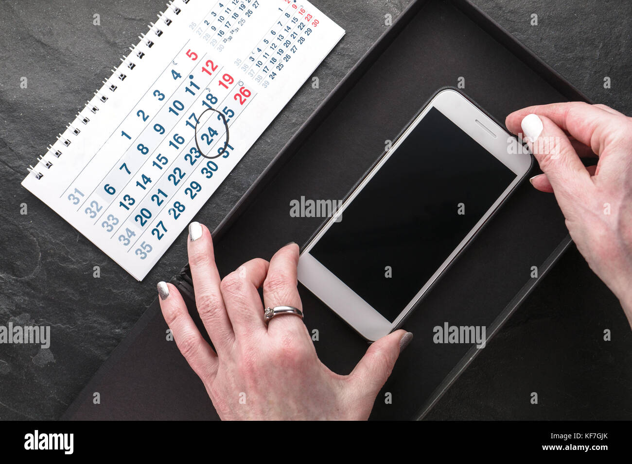Calendar, black box and phone in hands view from above horizontal Stock Photo