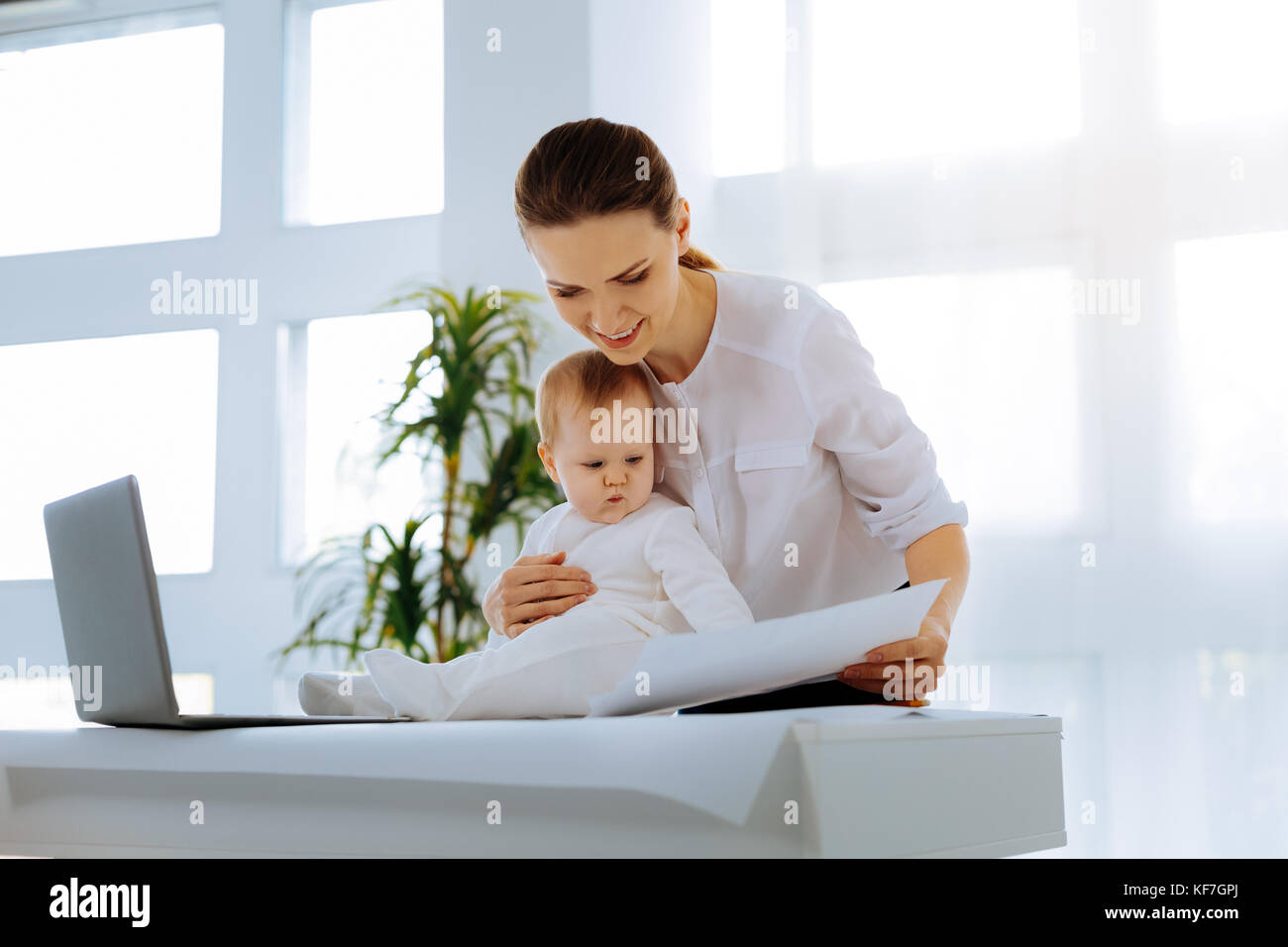 Serious baby being involved in the job of his mother Stock Photo
