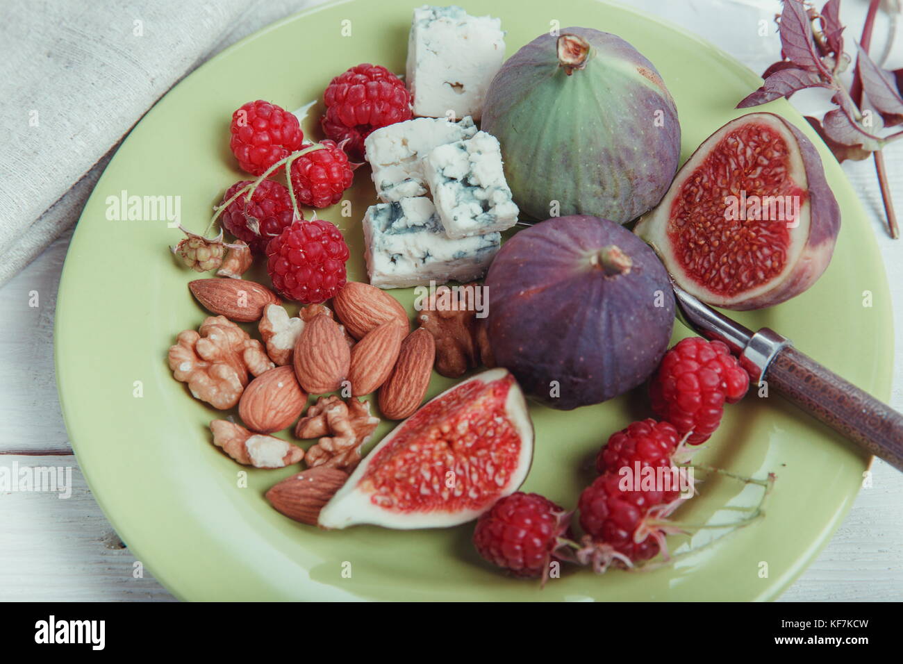 Serving the table, fresh figs, fruits, berries, cheese, nuts on a white