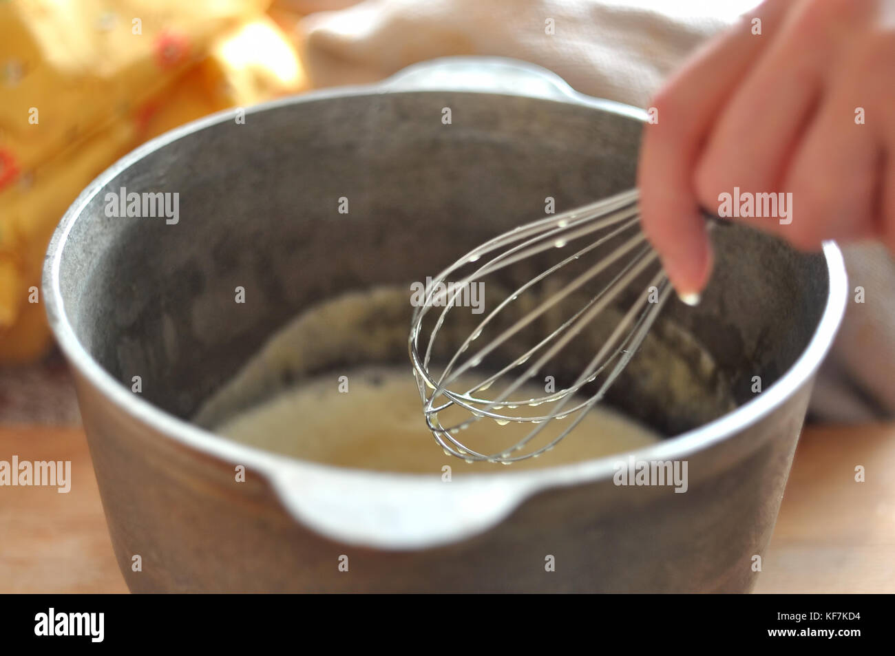 Female hand is whisking batter in castiron bowl, closeup, selective