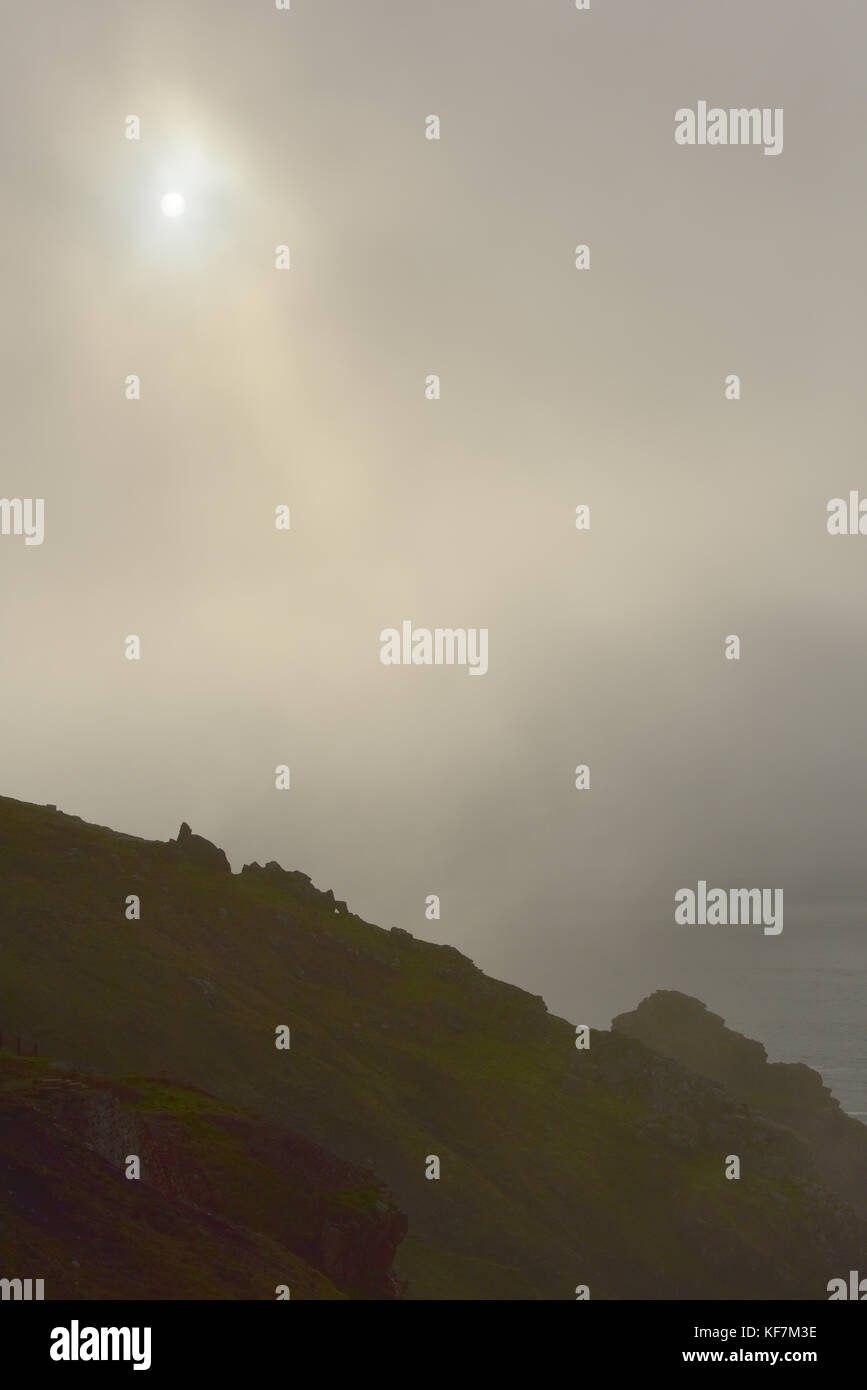 A cornish coastal sunset through dense sea mist giving and ethereal and