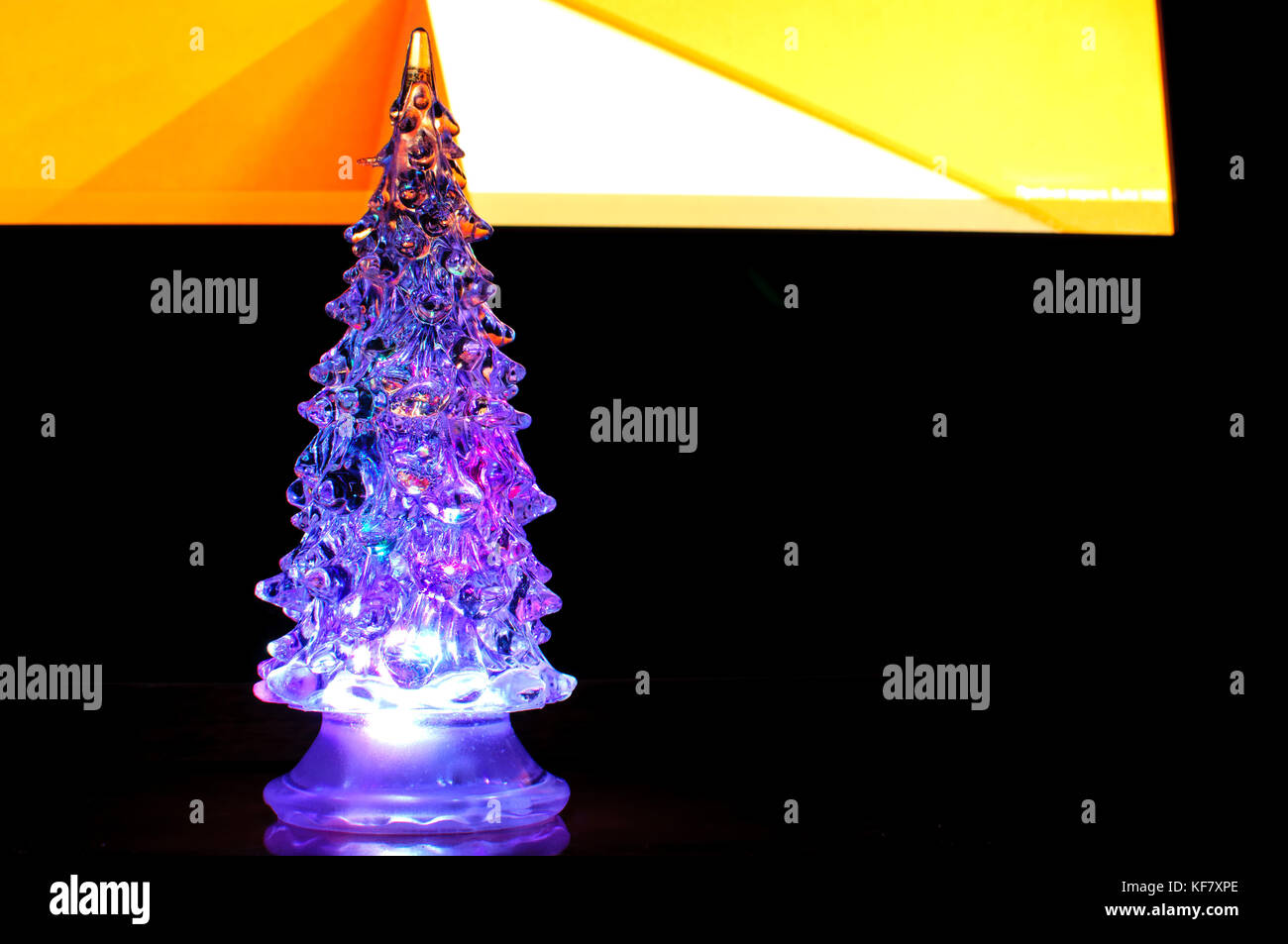 A small lighting Christmas tree on the contrast dark and orange