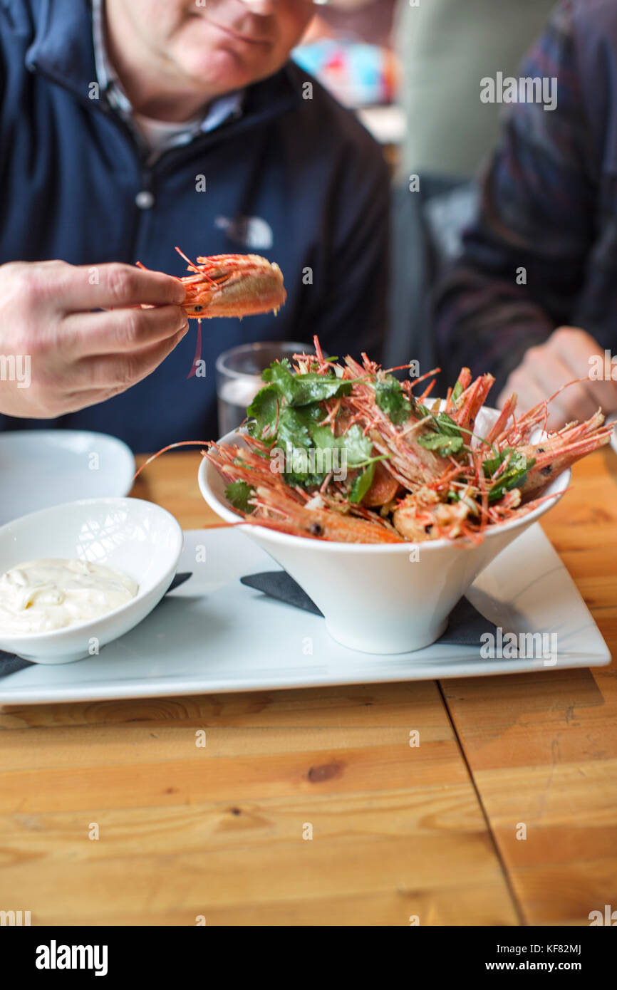 CANADA, Vancouver, British Columbia, a man eats fried shrimp heads at a local bistro, Edible Canada, located on Granville Island Stock Photo