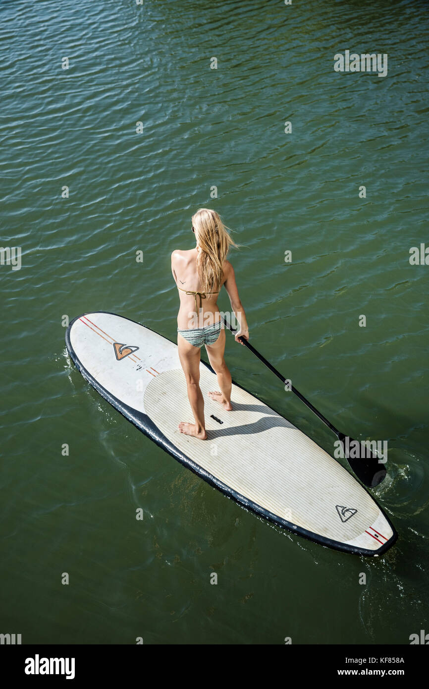 HAWAII, Oahu, North Shore, a young woman paddleboards on the Anahulu River below the historic Rainbow Bridge in the town of Haliewa Stock Photo