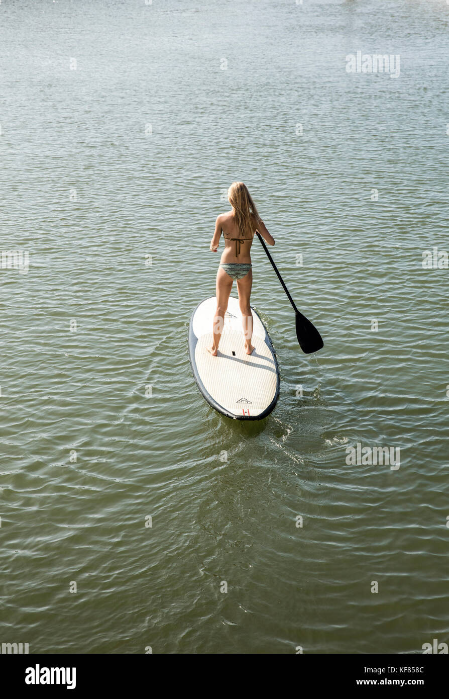 HAWAII, Oahu, North Shore, a young woman paddleboards on the Anahulu River below the historic Rainbow Bridge in the town of Haliewa Stock Photo