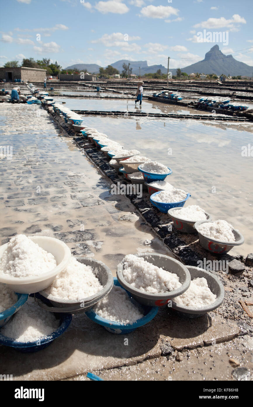 MAURITIUS, Tamarin, women carry heavy loads of salt to a storage facility where it is stored and prepared for transportation, Tamarin Salt Pans Stock Photo