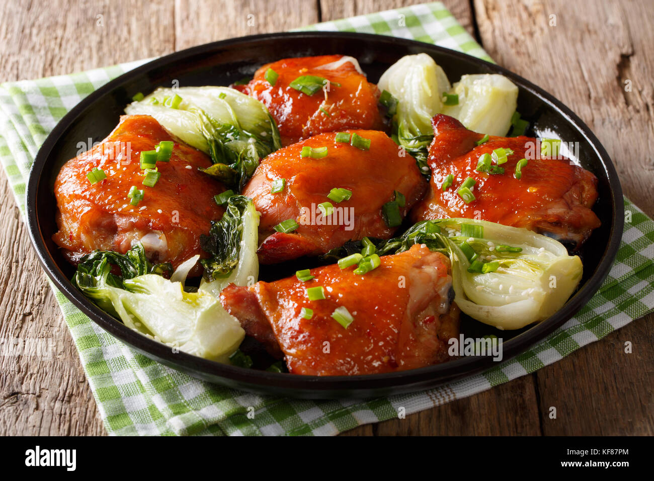 Traditional fried chicken thighs with bok choy, ginger, garlic and green onions closeup on a