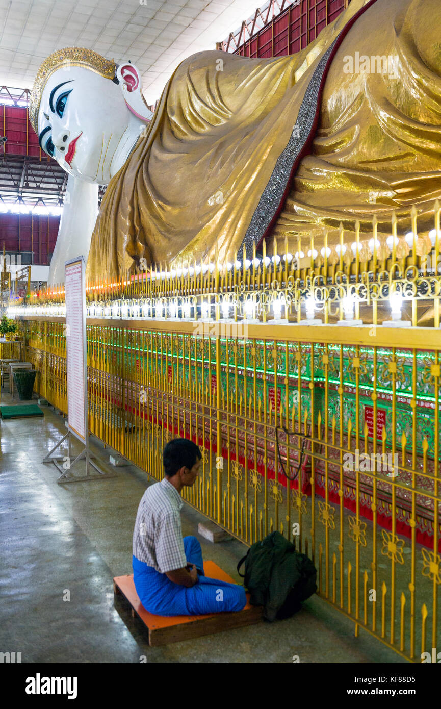 Myanmar (formerly Burma). Yangon (Rangoon). The Kyaukhtatgyi Pagoda is home to a large 70 meter long lying Buddha. Man praying Stock Photo