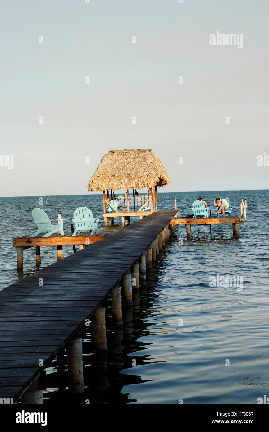 BELIZE, Caye Caulker, tourists relax on a pier by the water at sunset Stock Photo