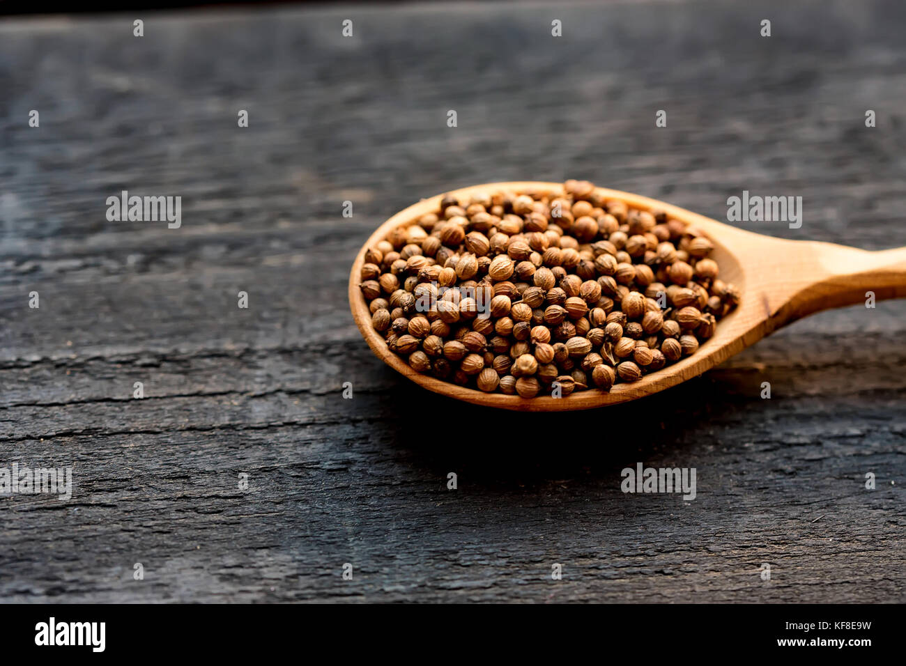 Coriander seeds in wooden spoon on wooden table Stock Photo