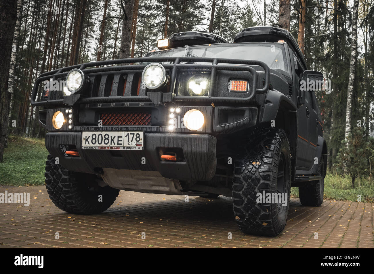 Saint-Petersburg, Russia - October 8, 2017: Black Hummer H2 car stands on rural parking lot in Russian countryside, close up photo, headlights on Stock Photo