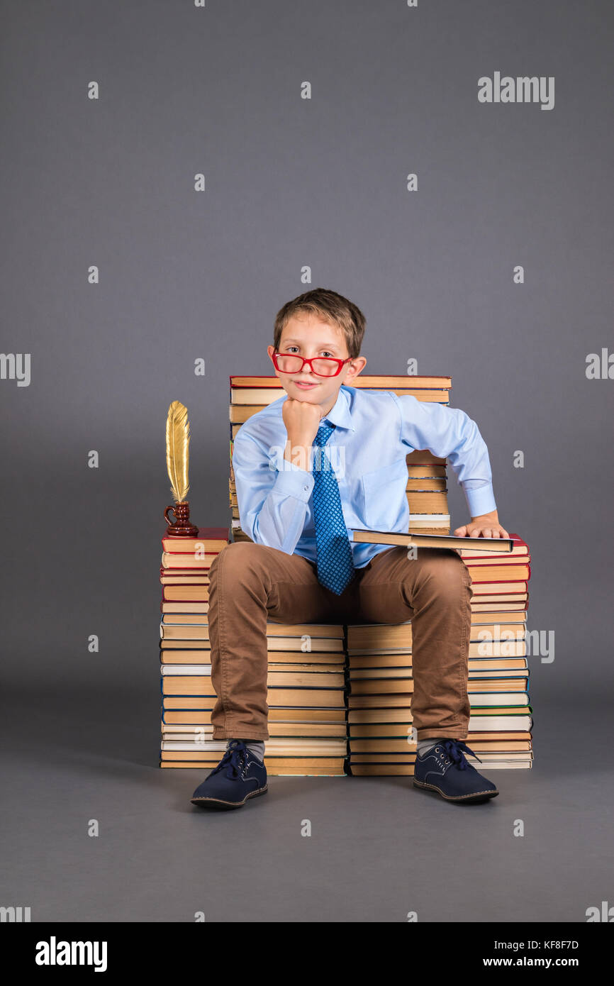 Education funny concept. A boy student sitting on a throne from books Stock Photo