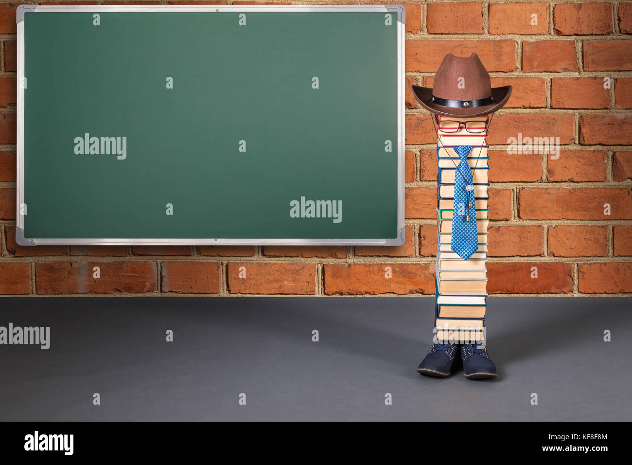 Funny education idea, man teacher near brick wall with blank chalkboard Stock Photo