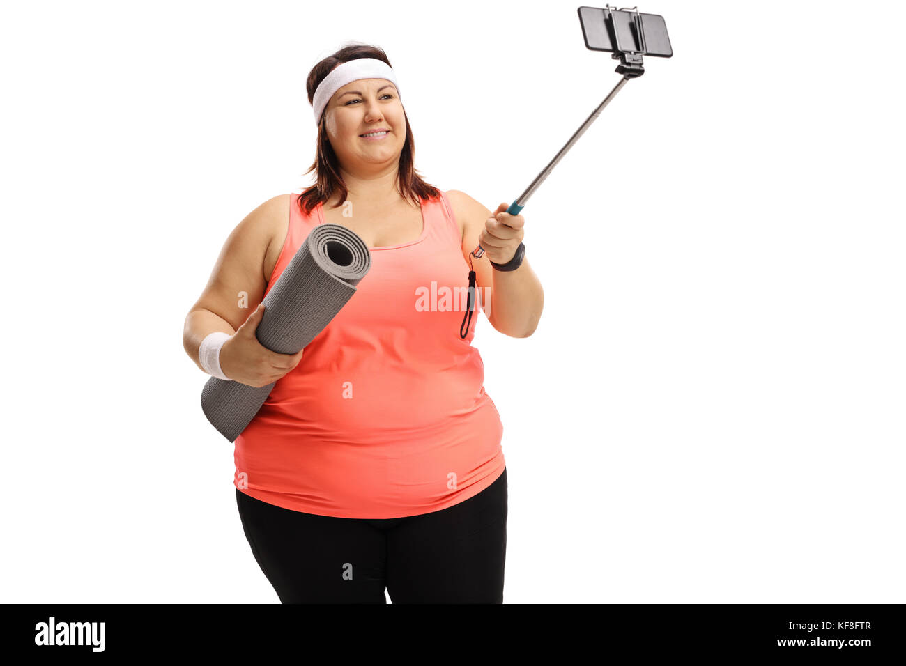 Overweight woman holding an exercise mat and taking a selfie with a stick isolated on white background Stock Photo