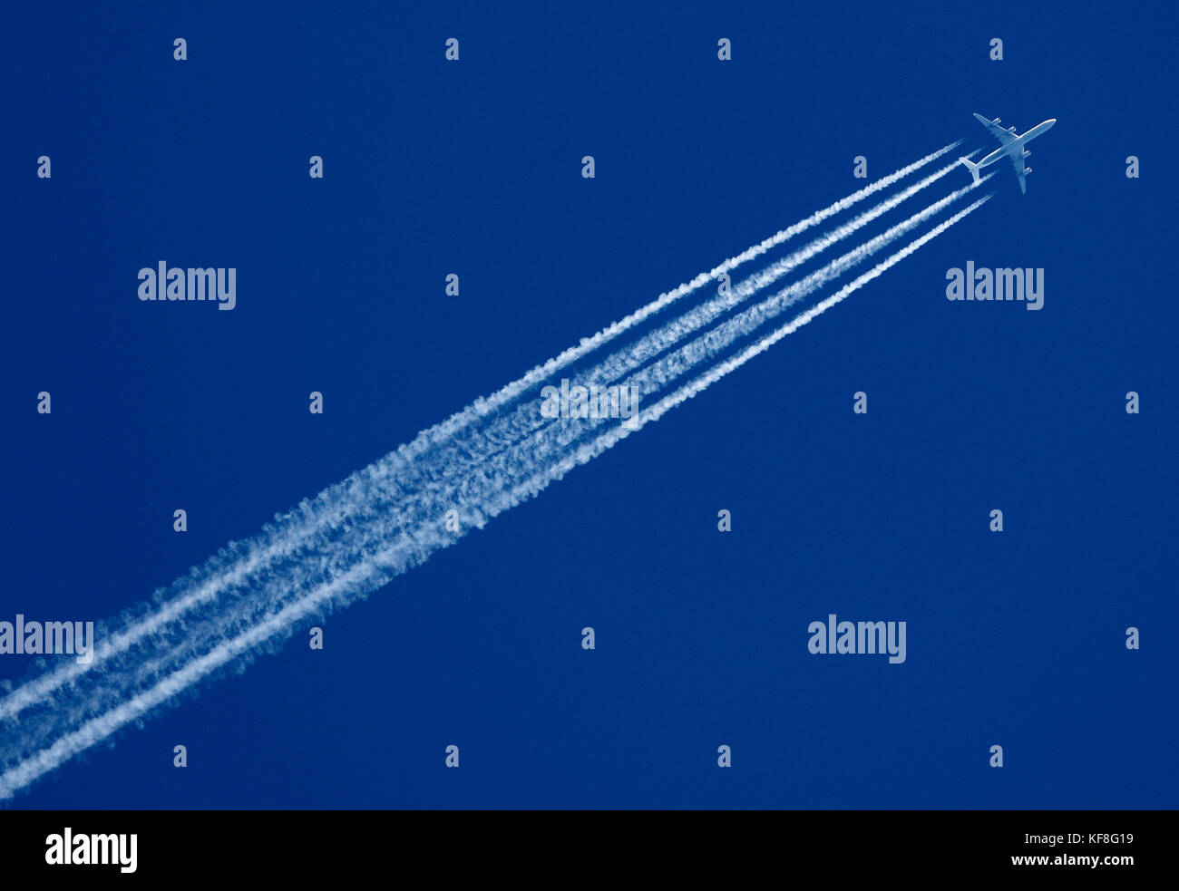 Jet aircraft in a clear blue sky leaving a white trail. Stock Photo