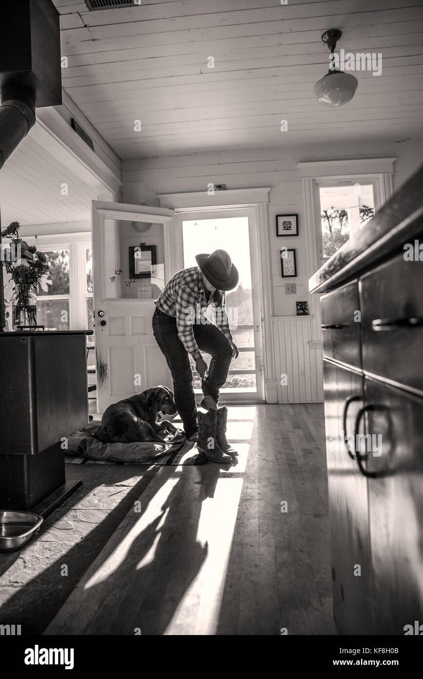 USA, Oregon, Willamette Valley, Clare Carver pulls on her boots in her