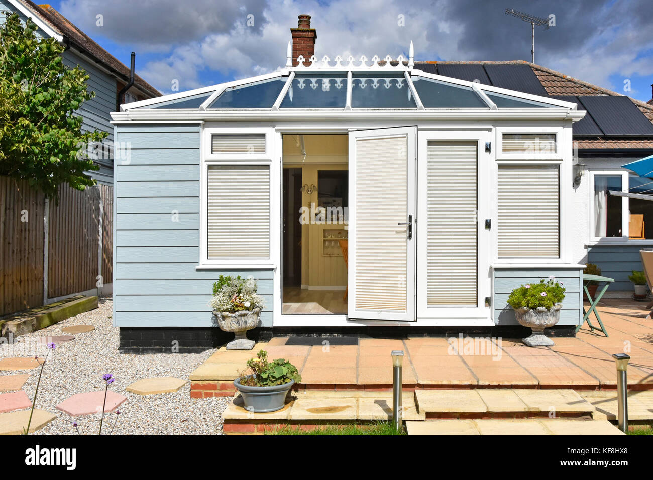 Back view of brick built bungalow solar panels & modern conservatory facing south extending into back garden blinds fitted to reduce summer heat UK Stock Photo