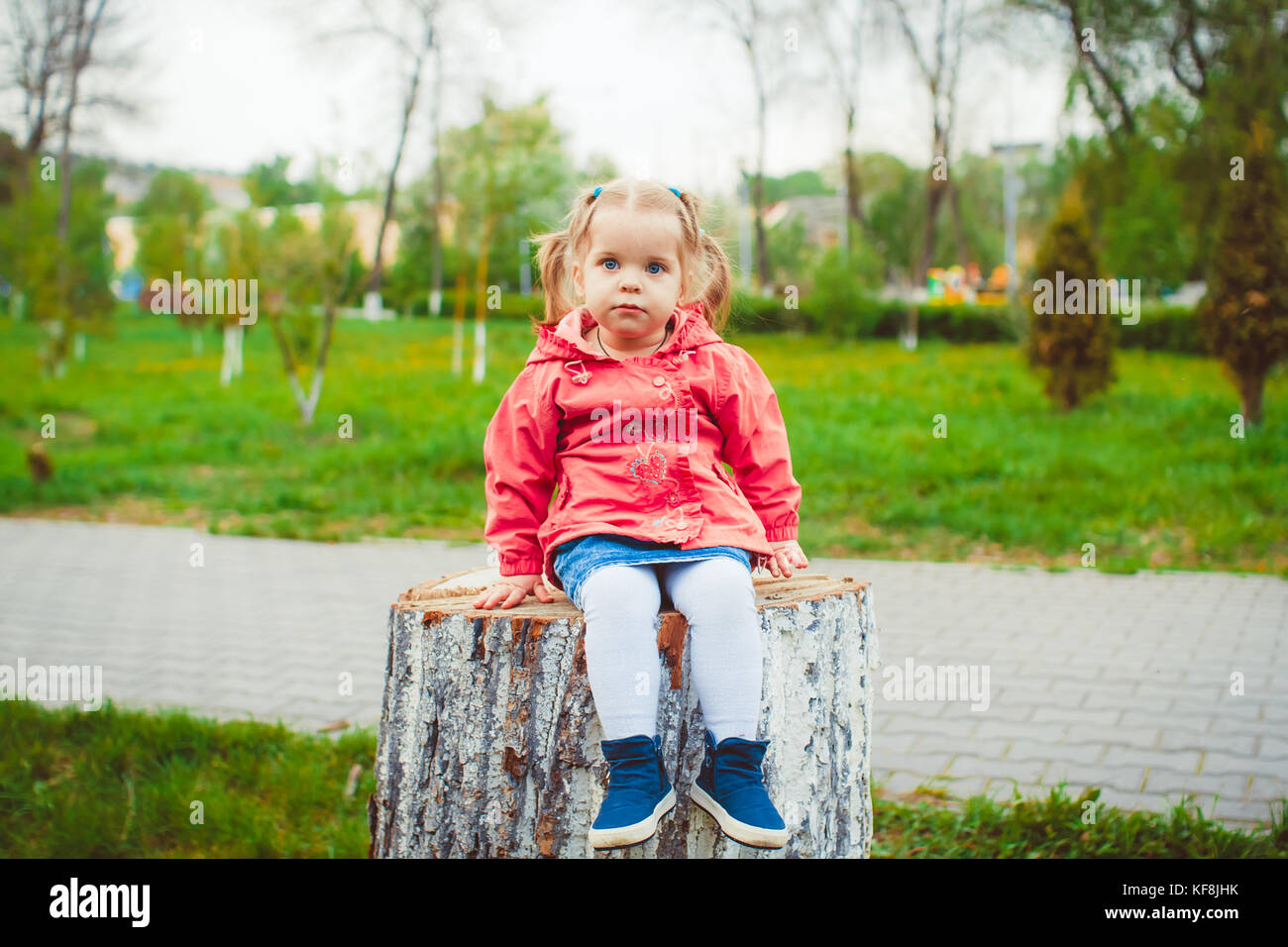 little girl sitting on a stump in the summer garden Stock Photo - Alamy
