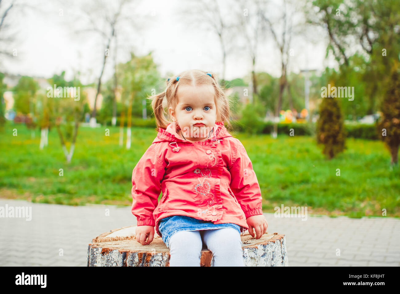 little girl sitting on a stump in the summer garden Stock Photo - Alamy