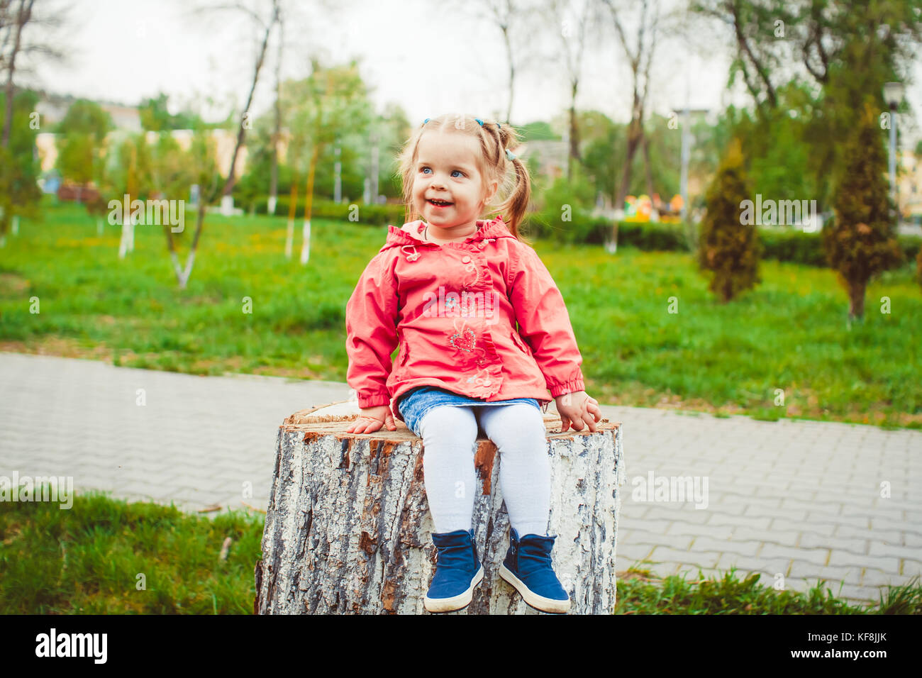 little girl sitting on a stump in the summer garden Stock Photo - Alamy