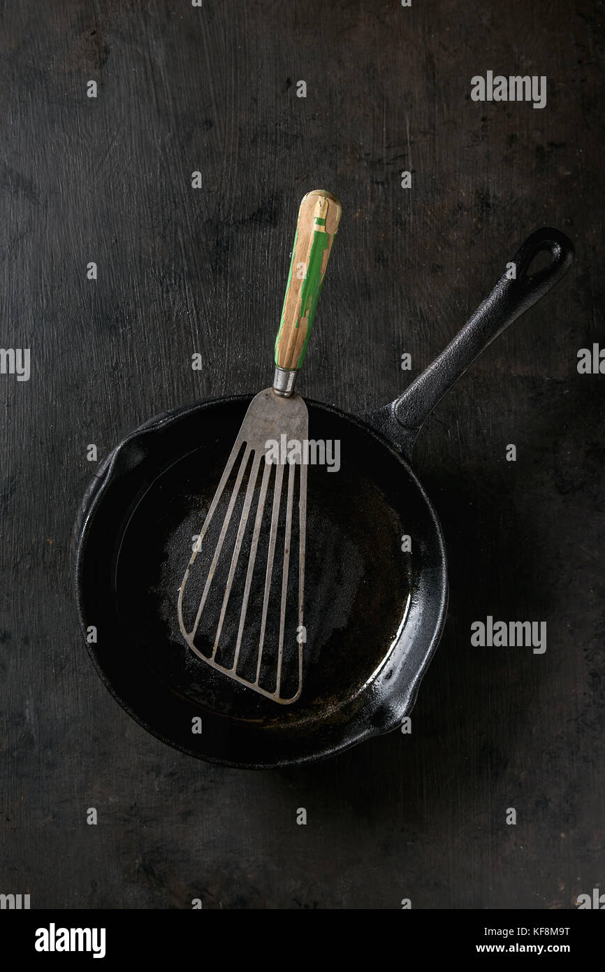 Empty oil castiron pan for cooking pancakes with vintage shovel over