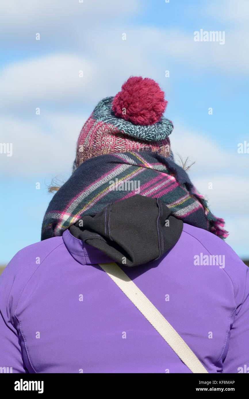 Woman wrapped up in warm winter clothing - coat, hat and scarf on cold winters day Stock Photo