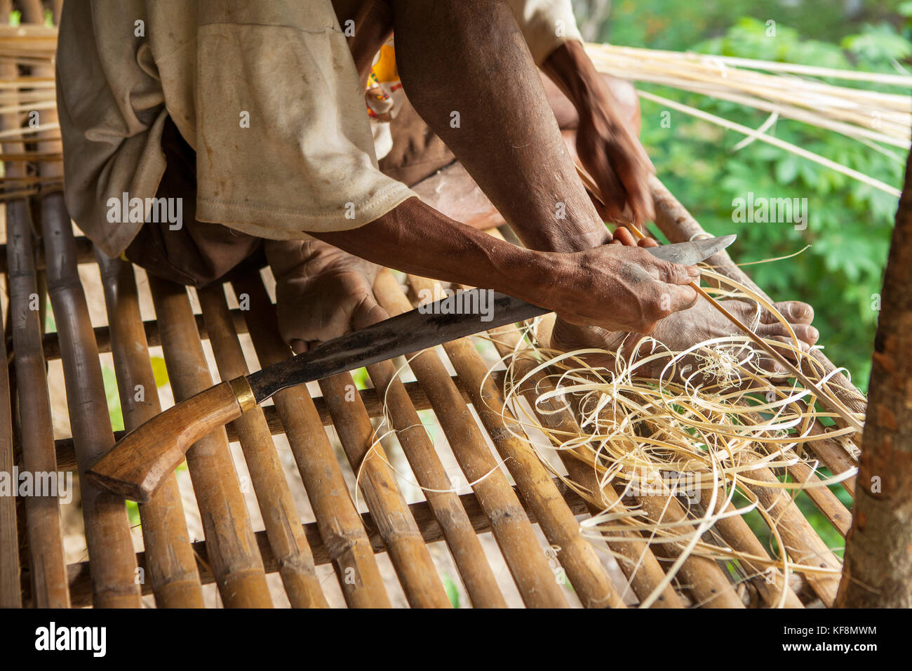 PHILIPPINES, Palawan, Barangay region, a Batak man shaves thin long piceces of bamboo that are used to tie the structural poles of their huts together Stock Photo