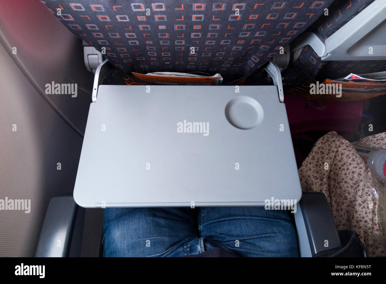 Plane / aeroplane passenger seat tray table in the full down position and ready for use, with passenger knees below, on an Airbus A320-214 operated by Easyjet. (91) Stock Photo