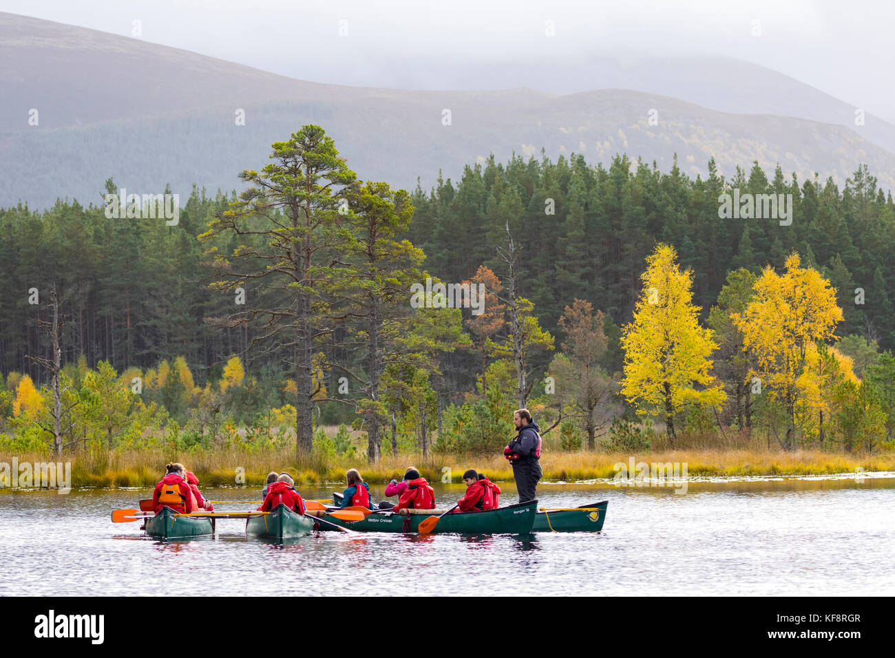 School children enjoying adventure sports on Uath Lochan with their instructor in autumn among the Inshriach Forest in the Scottish Highlands, UK Stock Photo