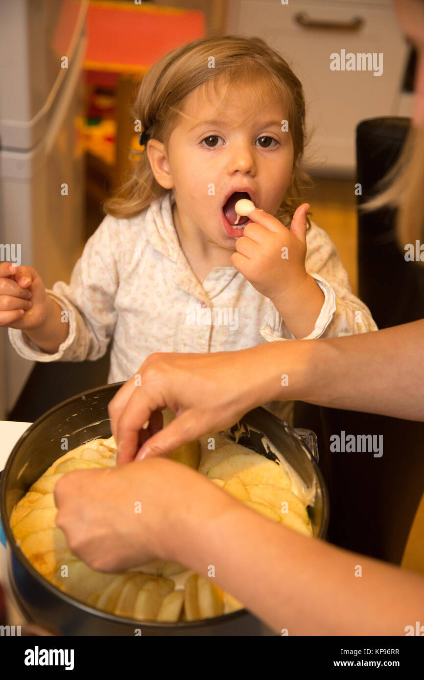 A young toddler girl licking the mixture prepared for a cake. She is
