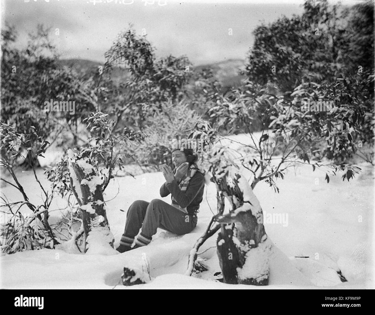 A woman skier making up her face amid the snow gums, c. 1930s, by Sam Hood Stock Photo