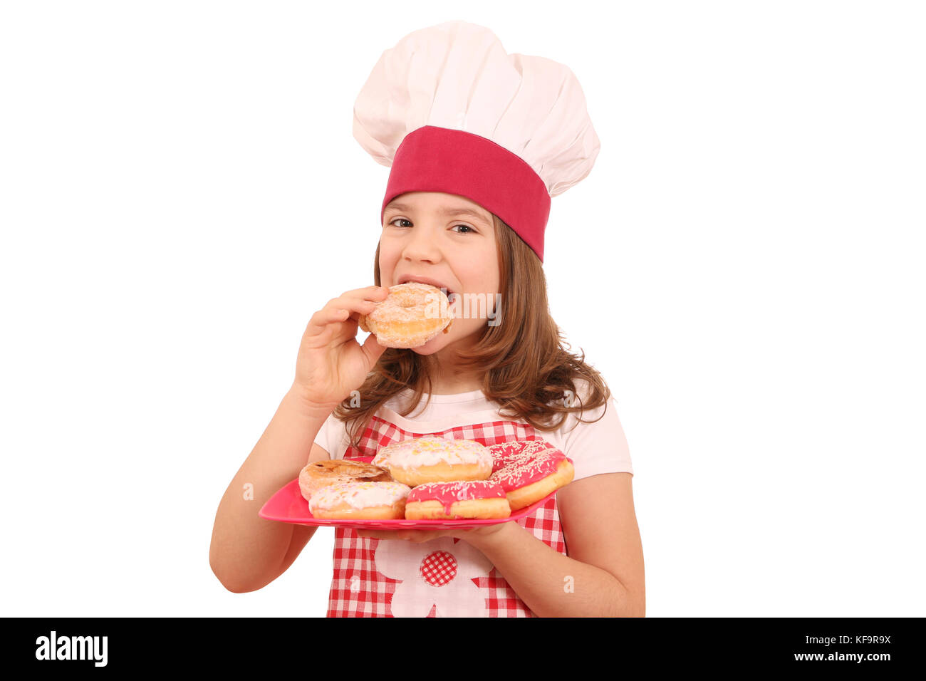 little girl cook eating sweet donuts Stock Photo