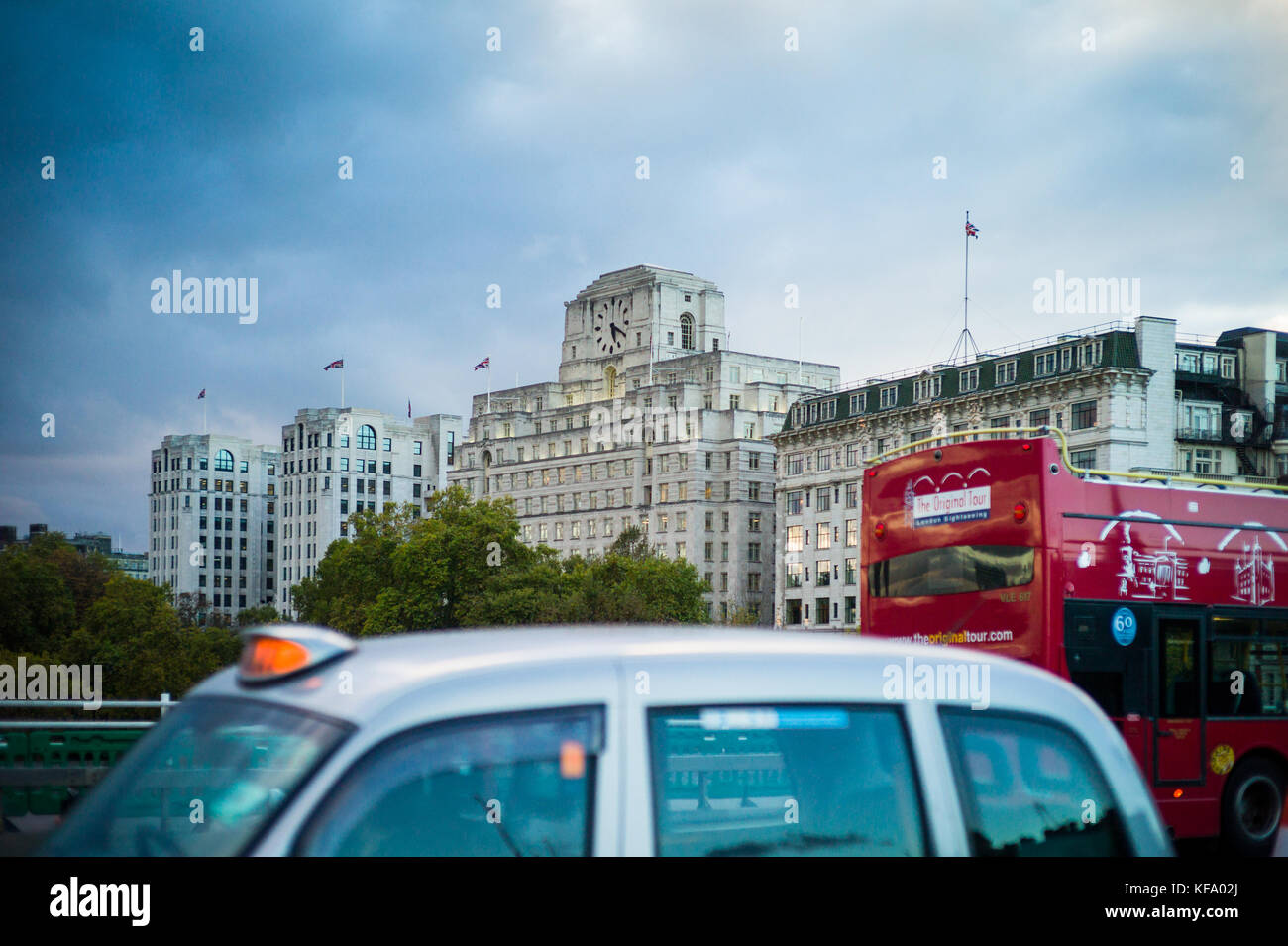 Shell Mex House - London bus and taxi cross Waterloo Bridge in front of Shell Mex House in central London at dusk Stock Photo
