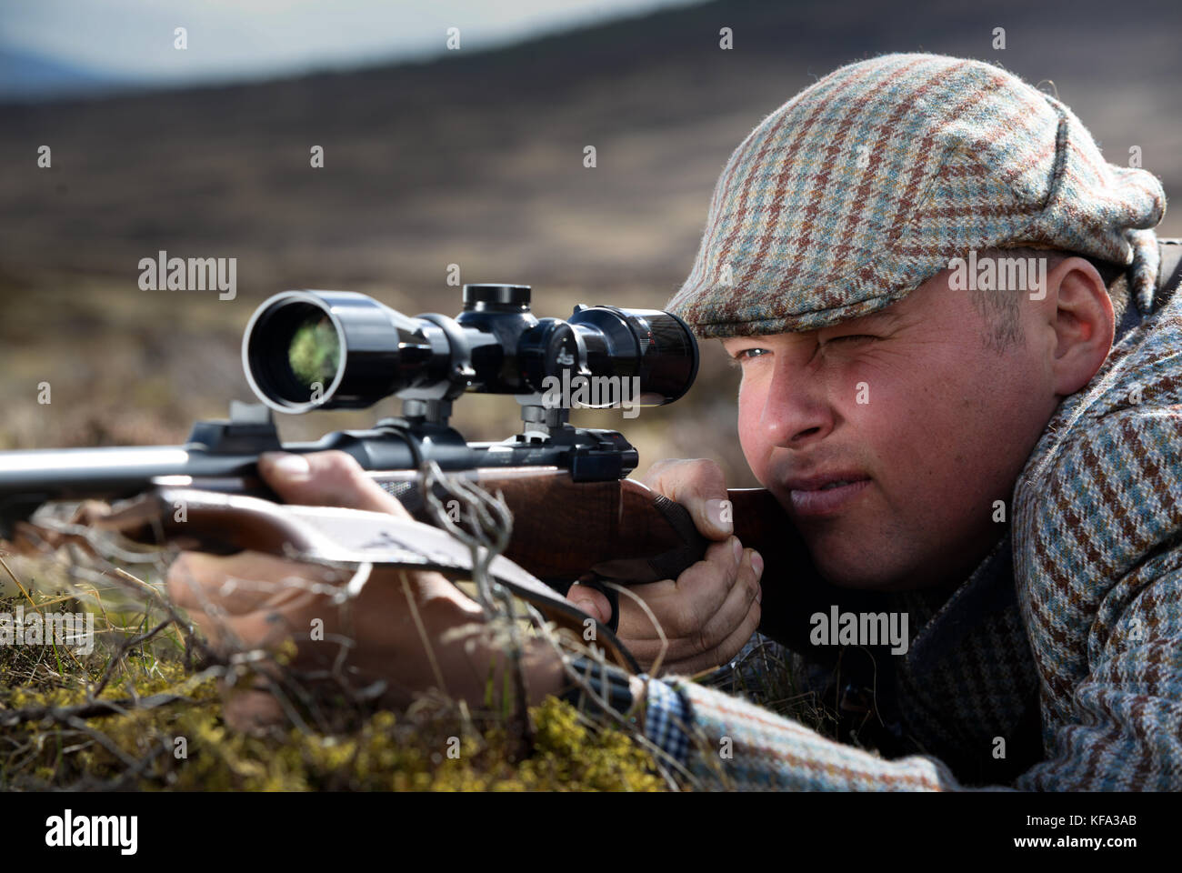 Deer stalker aiming rifle with telescopic sight Stock Photo