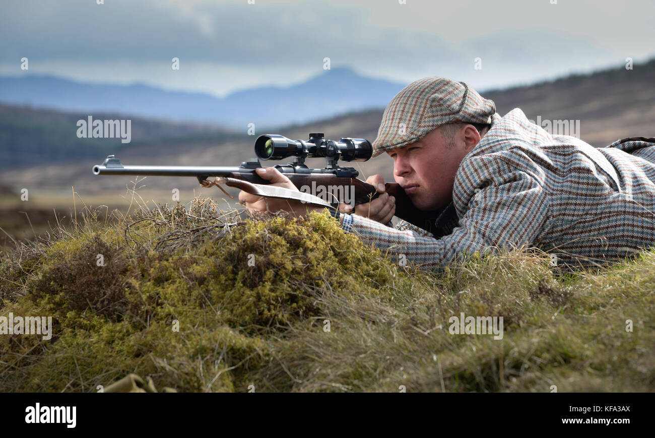 Deer stalker aiming rifle with telescopic sight Stock Photo