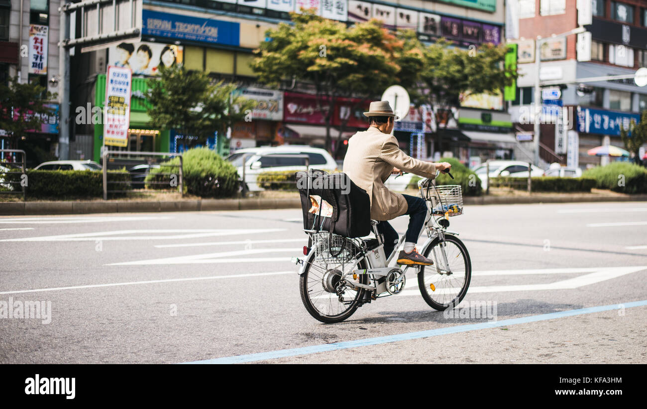 Elderly korean man riding his bike through streets of seoul Stock Photo
