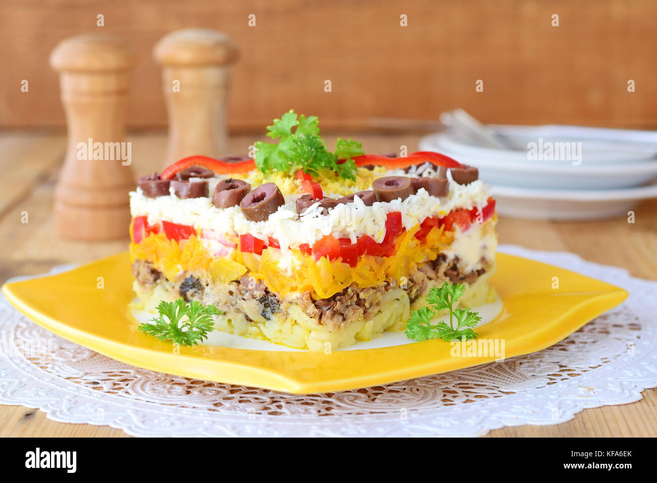 Traditional Russian layered salad Mimosa composed of canned fish covered with layers of boiled potato, carrot, onion, cheese, eggs and mayonnaise. Stock Photo