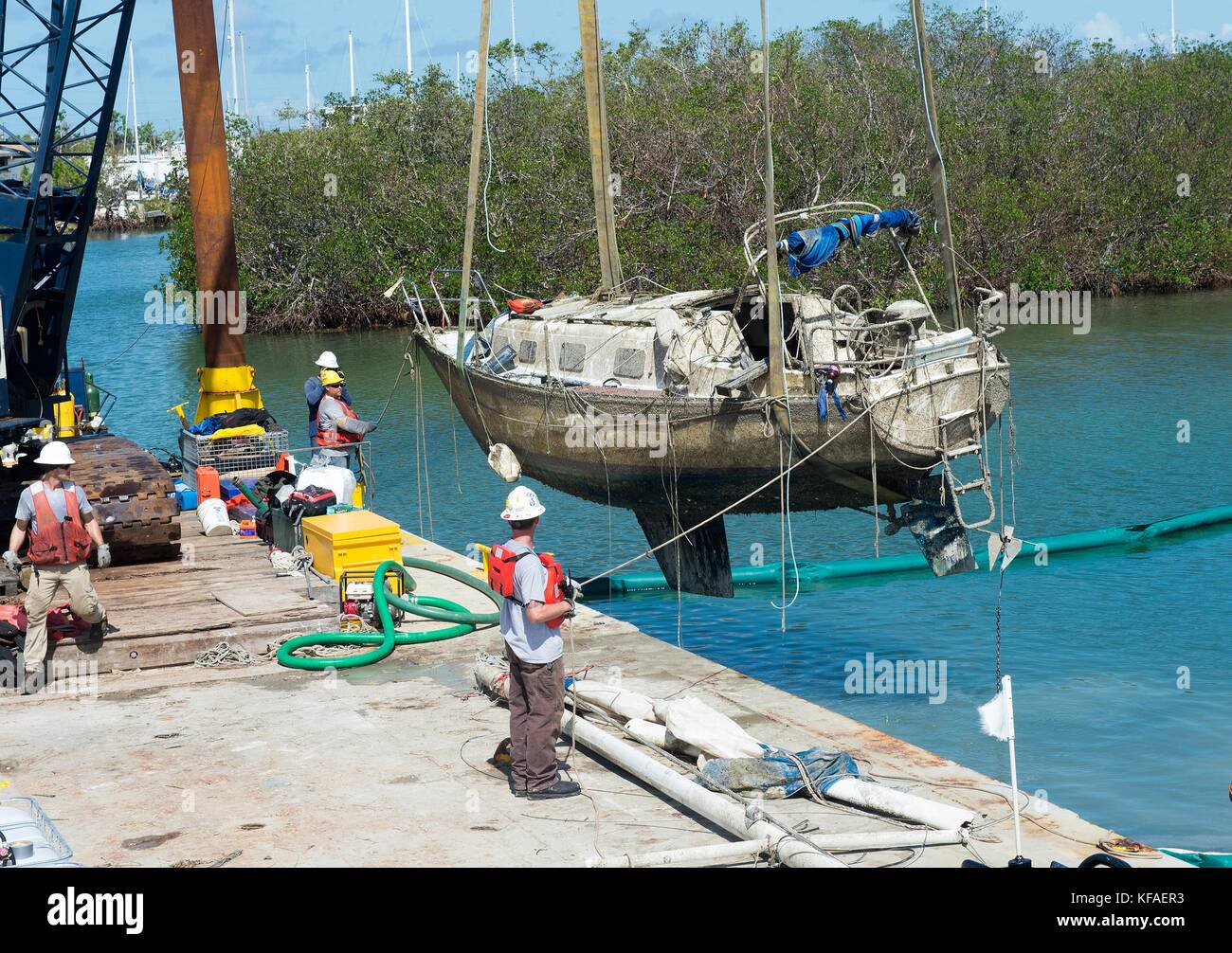 U.S. Coast Guard officers and response crews remove damaged boats from ...
